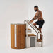 Man climbing wooden steps leading to a sauna on a white background
