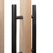 Close-up of black metal handles on wooden panels with a white background