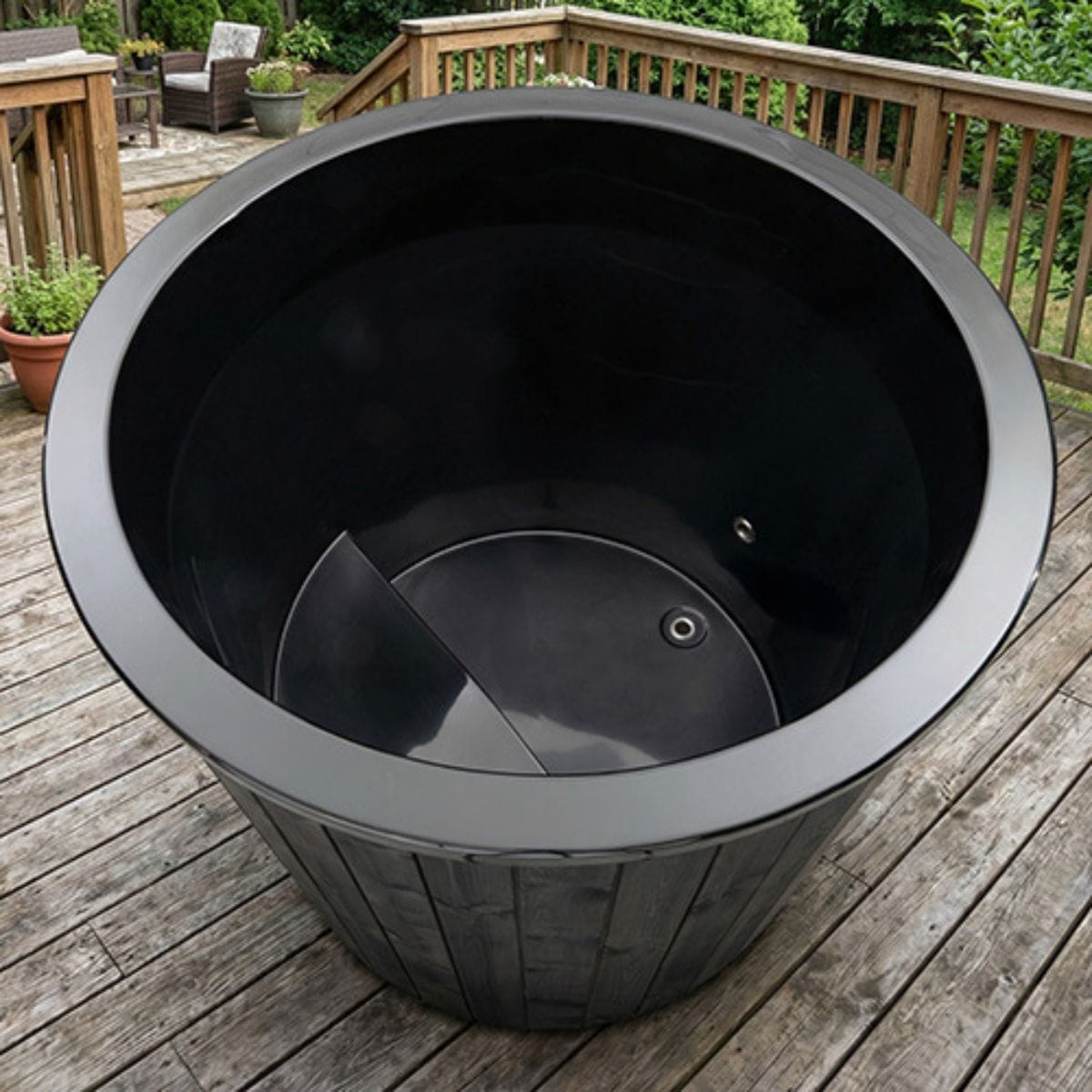Black plastic planter on a wooden deck with outdoor furniture in the background