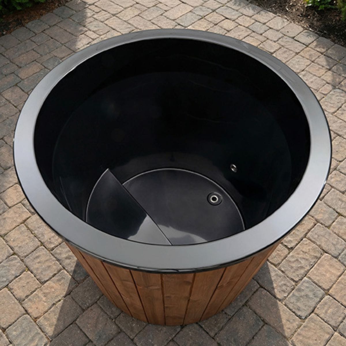 Black trash bin with wooden base on a paved surface