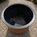 Black trash bin with wooden base on a paved surface
