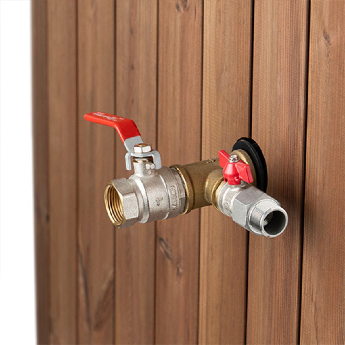 Brass outdoor faucet with red handles attached to a wooden wall.