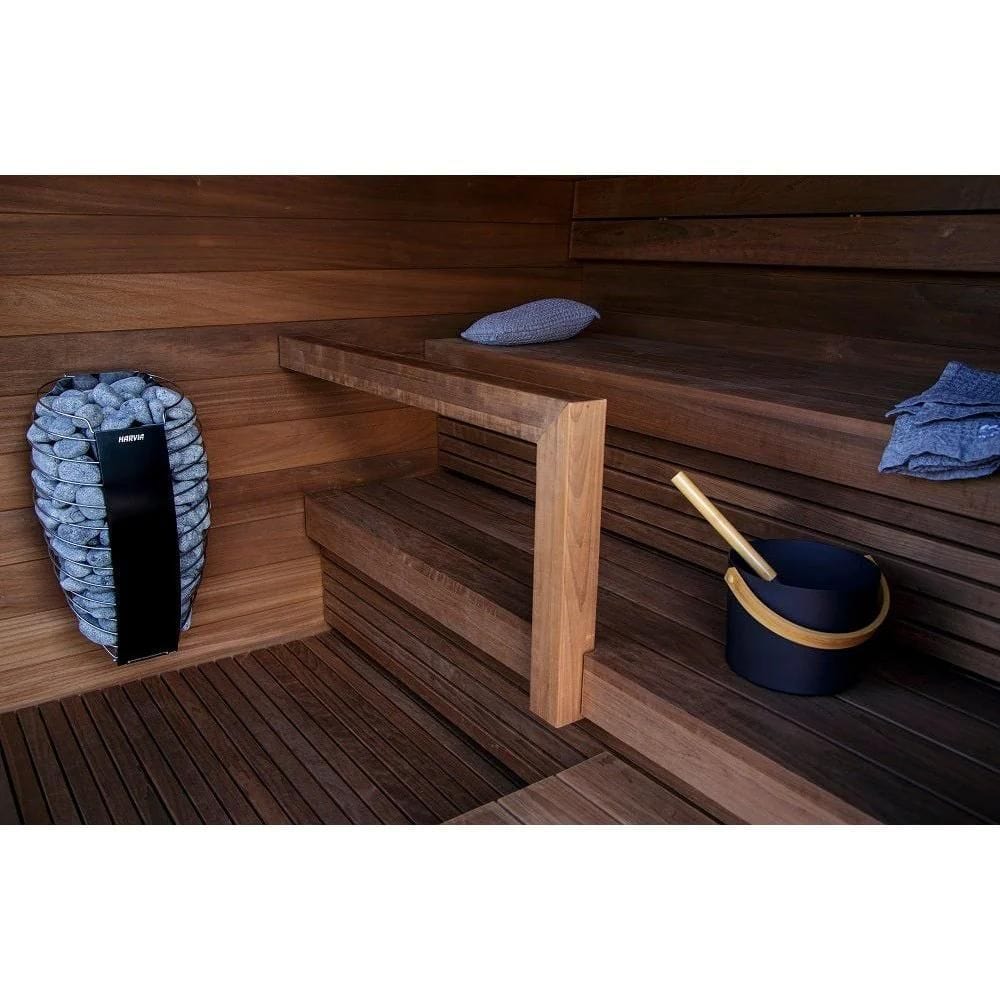 Wooden sauna interior with a bench, bucket, and towels.