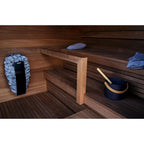 Wooden sauna interior with a bench, bucket, and towels.